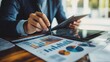 © WS Studio 1985 - Young Entrepreneur Reviewing Investment Strategies with Tablet and Documents on a Wooden Desk, Focused on Financial Growth and Analysis in a Modern Office Setting