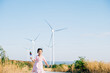 © sorapop - Child's playful exploration by windmills, little girl runs with pinwheels. Embracing wind energy education promoting clean electricity and sustainable industry in a beautiful setting.