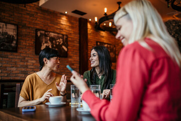 Wall Mural - Happy young people enjoy coffee and chat, gathering in a relaxed and social environment.