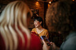 © La Famiglia - Photo of cheerful friends during a dinner party in an indoors bistro, having fun while taking photos and selfies