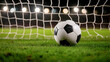 © Virtual Art Studio - Close-up of classic black and white soccer ball on lush green pitch in front of goal net, with soft stadium lights creating dramatic evening ambiance.