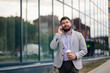 © Zamrznuti tonovi - Businessman walking and talking on phone outside office building