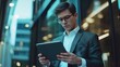 © Nathan - A young Caucasian man in a suit examines a tablet, exuding focus and professionalism in a contemporary office setting.