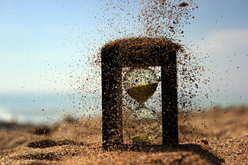 Wall Mural - Sand falls on an hourglass on the seashore against the sky