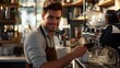 © Nathan - A young Caucasian male barista smiles while preparing coffee in a cozy café.