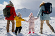© Halfpoint - Young family is enjoying winter holiday in the mountains, holding hands while walking through the snowy landscape.