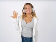 © Roquillo - Beautiful teen girl wearing white jacket smiling and looking friendly, showing number five or fifth with hand forward, counting down