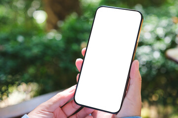 Wall Mural - mockup image of a woman holding mobile phone with blank white desktop screen in the outdoors