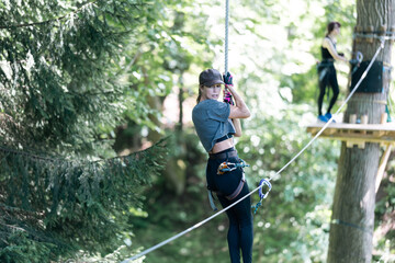 Wall Mural - a woman joyfully ziplines through a vibrant forest, capturing a thrilling sense of adventure in natu