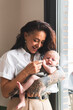 © Westend61 - Happy woman holding cute baby girl at home