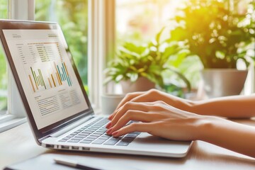 A person working on a laptop with charts and graphs, showcasing productivity in a bright and green environment.