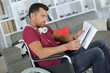 © auremar - focused disabled man on wheelchair reading newspaper at home