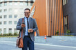 © Dragana Gordic - Confident Businessman Checking Phone While Walking Outside Office Building