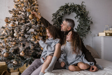 Wall Mural - A father and his two daughters create lasting holiday memories while decorating a stunning Christmas tree.