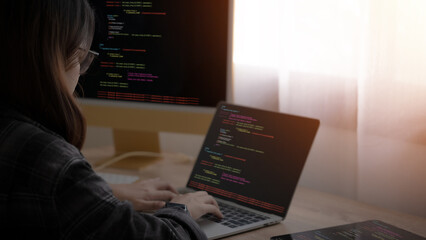 Wall Mural - a woman is typing on a laptop computer. she is wearing glasses and is focused on her work. the lapto