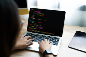 Wall Mural - a woman is typing on a laptop computer. the screen is black and the keyboard is silver. the woman is