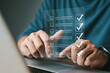 © Henhen - Person using a futuristic touchscreen interface with checklist items over a laptop.