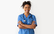 © Prostock-studio - Portrait of positive female African American doctor or nurse posing with crossed arms and smiling looking at camera isolated over white studio background wall, lady wearing blue coat and stethoscope