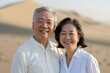 © Markus Schröder - Portrait of a grinning asian couple in their 50s wearing a classic white shirt over backdrop of desert dunes