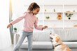 © Prostock-studio - Dog Training Commands Concept. Positive black girl teaching pet at home in living room, playing with golden retriever and rewarding him with treats, standing indoors and giving animal food