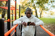 © Marko Geber - Older man in hoodie listening to music with headphones outdoors at workout park