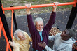 © Marko Geber - Senior men exercising together on pull-up bar in outdoor park fitness area