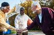 © Marko Geber - Senior men playing basketball outdoors team huddle