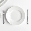 © ANILCHANDRO - White empty plate with spoon and fork in a dining setting isolated on white a background