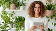 © Rachakrit - A smiling woman with curly hair holds a tablet in a green, plant-filled space, exuding a cozy and cheerful vibe.