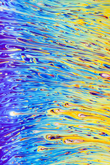 Wall Mural - Real photograph of a colorful light diffraction on a soap bubble surface with random swirls, curves and lines that look like waves on water during a sunset