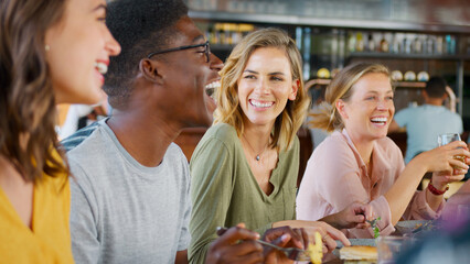 Wall Mural - Group Of Young Friends Meeting For Drinks And Food In Restaurant Or Bar