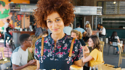 Wall Mural - Portrait Of Female Server In Busy Bar Restaurant Smiling At Camera