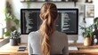 © Emiliia - Woman working on programming code at a computer desk surrounded by plants in a modern workspace