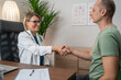 © Nenad - Doctor and patient shaking hands.  Female doctor and a male patient shake hands in the clinic. The doctor smiles warmly as they greet each other, marking the beginning of their consultation in a pro