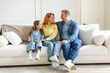 © Home-stock - Joyful parents and daughter sitting on soft comfortable couch in cozy home interior, promoting mortgage, property buying, full length shot, free space