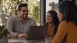 © Nataliya - A vibrant image of a happy Hispanic real estate agent sitting at a modern desk, enthusiastically showing a property to a young Latinx couple on a sleek laptop screen. The couple le