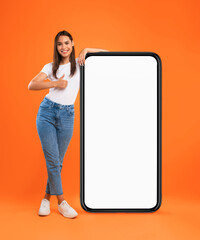 Wall Mural - mobile offer. happy woman leaning on huge cellphone with blank white screen, showing thumb up gestur
