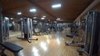 © Enggal Pitoyo - Spacious, well-equipped gym with various workout machines and wooden floors.