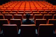 © Ева Поликарпова - A person sitting in an auditorium with rows of orange chairs, suitable for use in event or performance scenarios
