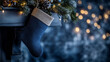 © Alexandra Adele - Decorative blue Christmas stocking hanging near a winter-themed mantelpiece with soft lights and festive greenery