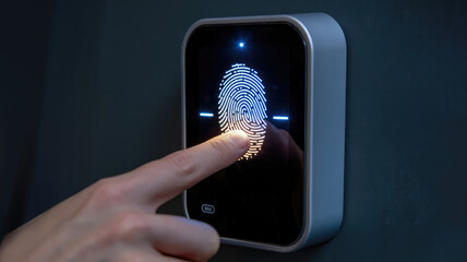 A person is touching a fingerprint sensor. The sensor is black and silver