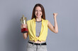 © New Africa - Happy winner with gold trophy cup on gray background