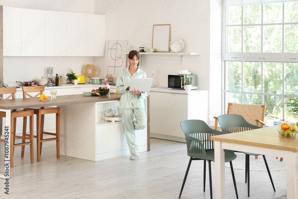 Young woman using laptop in kitchen