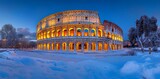 A panoramic view of the Colosseum in Rome, illuminated and surrounded by snow.