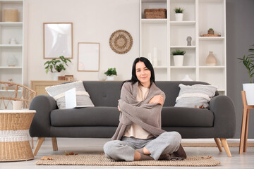 Wall Mural - Beautiful young happy woman with warm plaid sitting on floor at home