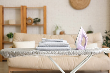 Sticker - Iron and stack of bed sheets on ironing board at home