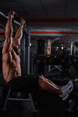 Wall Mural - A Caucasian man hangs on a horizontal bar and raises his legs. Vertical photo. 