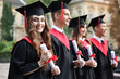© New Africa - Happy students with diplomas after graduation ceremony outdoors, selective focus