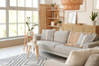 © Pixel-Shot - Interior of light living room with grey sofa, shelf unit and plants