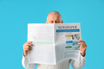 Senior businessman with newspaper on blue background